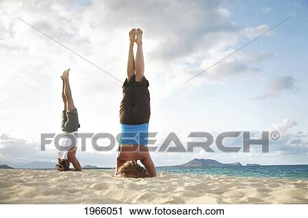 Hawaii, Oahu, Lanikai, Young Couple Doing Yoga, Stay In A Headstand Position On The Beach. View Large Photo Image Stock Image - Hawaii, Oahu, Lanikai, Young Couple Doing Yoga, Stay In A Headstand Position On The Beach.. Fotosearch