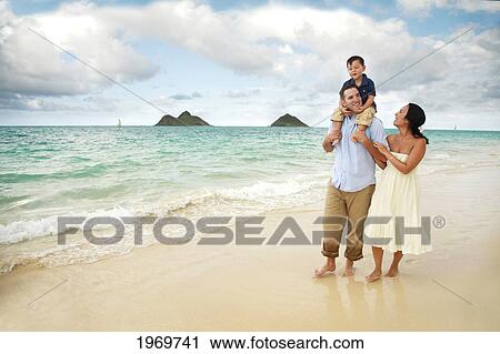 Stock Image - Hawaii, Oahu, Lanikai, Young Family Strolling Along The Beach.. Fotosearch