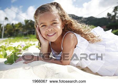 Stock Photo - Hawaii, Oahu, Lanikai, Young Girl Poses Laying In Sand With Hand On Her Cheek.. Fotosearch