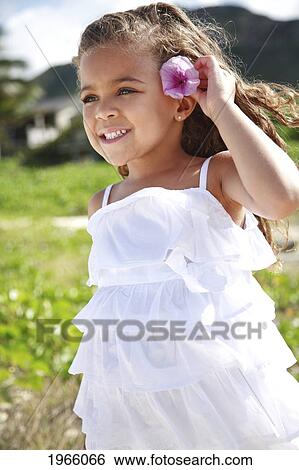 Hawaii, Oahu, Lanikai, Young Girl Puts Purple Flower Behind Her Ear. View Large Photo Image Stock Photograph - Hawaii, Oahu, Lanikai, Young Girl Puts Purple Flower Behind Her Ear.. Fotosearch