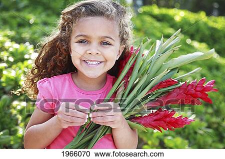Stock Image - Hawaii, Oahu, Lanikai, Young Girl Smiles At Camera With Bundle Of Ginger Flowers.. Fotosearch