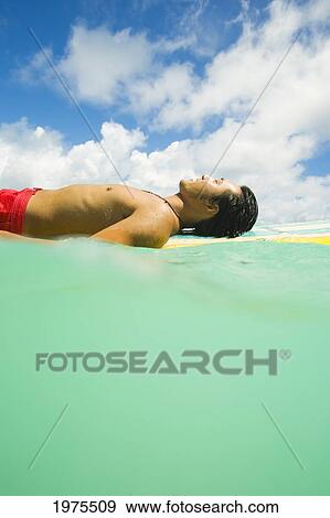 Stock Photo - Hawaii, Oahu, Lanikai, Young Japanese Man Lying On Surfboard In The Ocean.. Fotosearch