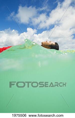 Stock Photograph - Hawaii, Oahu, Lanikai, Young Japanese Man Lying On Surfboard In The Ocean.. Fotosearch