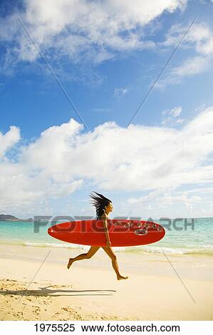 Stock Photography - Hawaii, Oahu, Lanikai, Young Japanese Woman Running On Beach While Holding A Red Surfboard.. Fotosearch