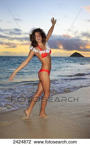Stock Image - Hawaii, Oahu, Lanikai, Young woman playing on beach during sunrise.. Fotosearch