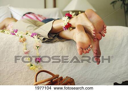 Hawaii, Oahu, Legs And Feet Of Couple In Hotel Bed, Lei Hanging From Toes. View Large Photo Image Picture - Hawaii, Oahu, Legs And Feet Of Couple In Hotel Bed, Lei Hanging From Toes.. Fotosearch