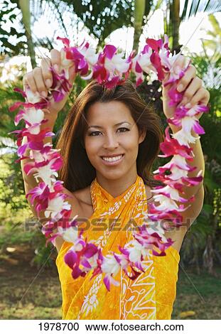 Stock Image - Hawaii, Oahu, Local Girl Wearing A Yellow Pareo Holds Out A Lei, Traditional Welcome.. Fotosearch