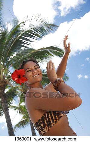 Stock Image - Hawaii, Oahu, Local Polynesian Hula Dancer Smiling And Dancing With Coconut Palm Trees In Background.. Fotosearch