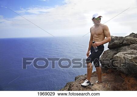 Hawaii, Oahu, Makapuu, Athletic Male Holding Water Bottle Taking A Break At Makapuu Cliffs View Large Photo Image Stock Photo - Hawaii, Oahu, Makapuu, Athletic Male Holding Water Bottle Taking A Break At Makapuu Cliffs. Fotosearch