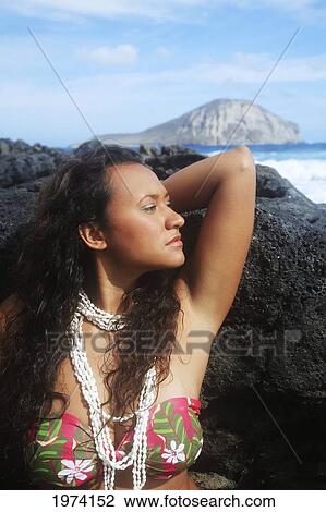 Stock Image - Hawaii, Oahu, Makapuu, Attractive Young Woman On The Rocks With Hawaiiana Attire.. Fotosearch