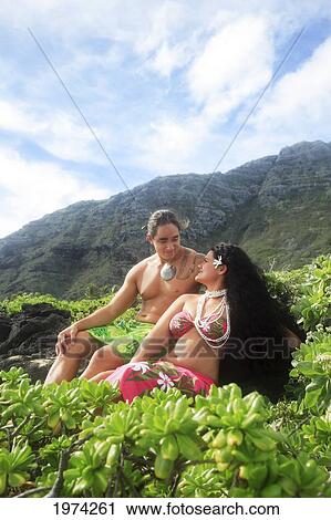 Stock Image - Hawaii, Oahu, Makapuu, Male And Female Hula Dancers Sit On The Shore. Fotosearch