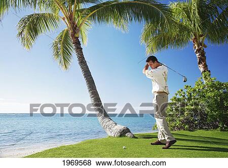Stock Photo - Hawaii, Oahu, Male Playing Golf, Ready To Swing His Golf Club At A Beach Front Golf Course. Fotosearch