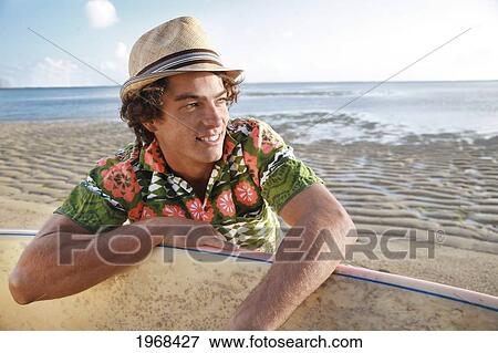 Stock Photo - Hawaii, Oahu, Male Relaxing On The Beach With His Surfboard Wearing Retro Hawaiian Shirt.. Fotosearch