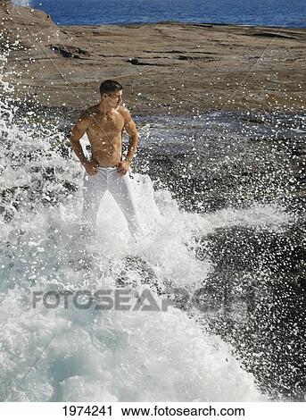Stock Image - Hawaii, Oahu, Male Wearing White Pants On Rocky Cliff.. Fotosearch
