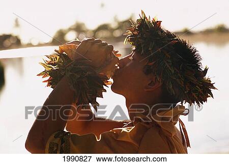 Hawaii, Oahu, Man Blowing Conch Shell In Hawaiian Dressings. Blurred Background. View Large Photo Image Stock Photo - Hawaii, Oahu, Man Blowing Conch Shell In Hawaiian Dressings. Blurred Background.. Fotosearch
