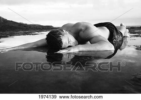 Hawaii, Oahu, Man Laying In Shallow Water On A Rocky Area. View Large Photo Image Stock Photo - Hawaii, Oahu, Man Laying In Shallow Water On A Rocky Area.. Fotosearch