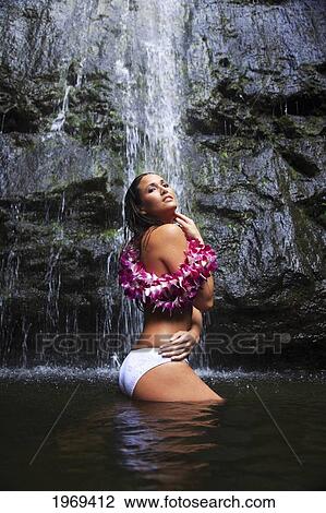 Stock Image - Hawaii, Oahu, Manoa Falls, Beautiful Female With Orchids Leis Sitting In A Pond At The Bottom Of Manoa Waterfalls.. Fotosearch