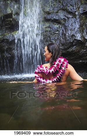 Stock Photo - Hawaii, Oahu, Manoa Falls, Beautiful Female With Orchids Leis Sitting In A Pond At The Bottom Of Manoa Waterfalls.. Fotosearch