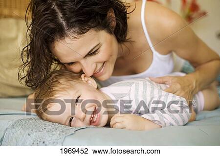 Stock Image - Hawaii, Oahu, Mother And Her Baby On The Bed.. Fotosearch