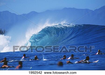 Stock Image - Hawaii, Oahu, North Shore, Group Of Surfers Swimming Out Over Break At Pipeline, Perfect Curling Wave.. Fotosearch