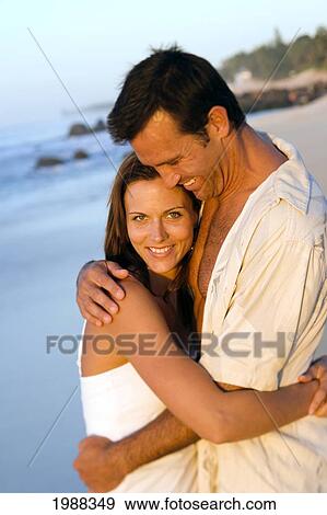 Stock Photo - Hawaii, Oahu, North Shore, Happy Couple Embracing On Beach In Warm Afternoon Light.. Fotosearch