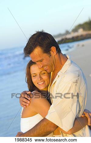 Stock Photography - Hawaii, Oahu, North Shore, Happy Couple Embracing On Beach In Warm Afternoon Light.. Fotosearch