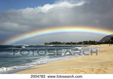 Stock Image - Hawaii, Oahu, North Shore, /Nbeautiful Bright Rainbow Arches Over Land And Sea.. Fotosearch