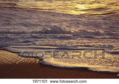 Stock Image - Hawaii, Oahu, North Shore, Reflection Of Sunset On Small Wave.. Fotosearch