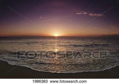 Stock Image - Hawaii, Oahu, North Shore, Water Lapping Onto Shore Of A Beautiful Sandy Beach At Sunset.. Fotosearch