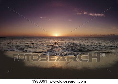 Stock Image - Hawaii, Oahu, North Shore, Water Lapping Onto Shore Of A Beautiful Sandy Beach At Sunset.. Fotosearch