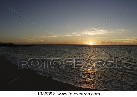 Stock Image - Hawaii, Oahu, North Shore, Water Lapping Onto Shore Of A Beautiful Sandy Beach At Sunset.. Fotosearch