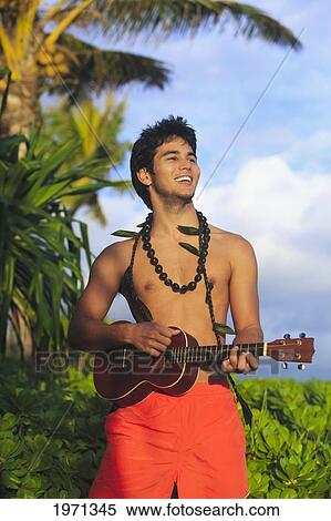Stock Photography - Hawaii, Oahu, Outdoor Portrait Of Young Polynesian Man Playing Ukulele.. Fotosearch