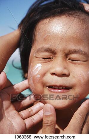 Stock Photo - Hawaii, Oahu, Parent Putting Sunscreen Lotion On Child's Face At The Beach. Fotosearch