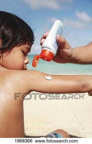 Stock Photograph - Hawaii, Oahu, Parent Putting Sunscreen Lotion On Child's Arm At The Beach. Fotosearch