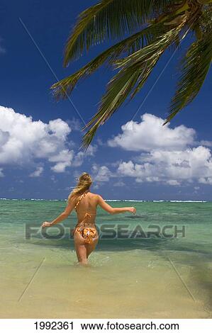 Stock Image - Hawaii, Oahu, Punaluu Beach, Beautiful Young Woman Wading In Turquoise Ocean.. Fotosearch