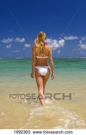 Stock Image - Hawaii, Oahu, Punaluu Beach, Beautiful Young Woman Walking Into Turquoise Ocean.. Fotosearch