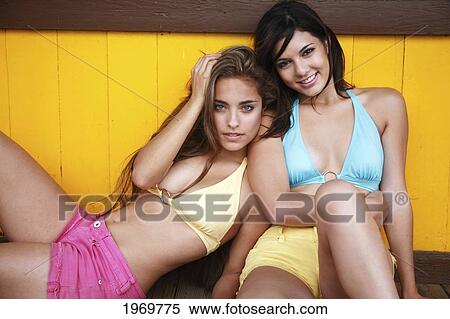 Stock Photography - Hawaii, Oahu, Two Beautiful Young Girls Sitting And Leaning Against Each Other. Editorial Use Only.. Fotosearch