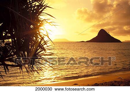 Stock Image - Hawaii, Oahu, View Of Chinaman's Hat At Sunset, Golden Light Shimmering On Ocean C1559. Fotosearch