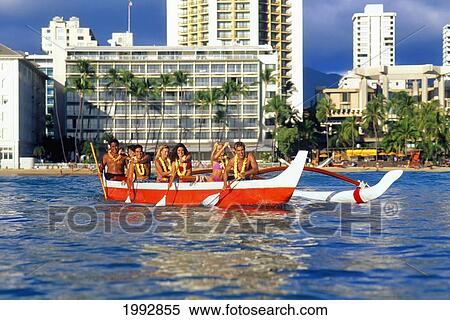 Stock Photography - Hawaii, Oahu, View Of Red And White Outrigger In Water, Hotels In Background, Paddlers Smiling. Fotosearch