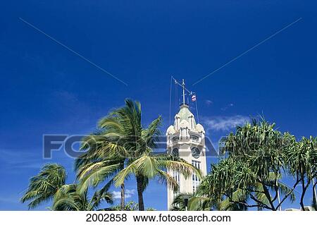 Stock Photo - Hawaii, Oahu, View Of The Top Of The Aloha Tower Against Blue Sky, Palms And Treetops. Fotosearch