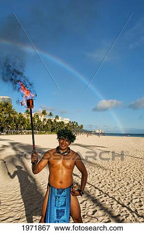 Hawaii, Oahu, Waikiki Beach, A Local Hawaiian Man Wears A Traditional Outfit, Holds A Torch With Rainbow In Background. View Large Photo Image Stock Photo - Hawaii, Oahu, Waikiki Beach, A Local Hawaiian Man Wears A Traditional Outfit, Holds A Torch With Rainbow In Background.. Fotosearch