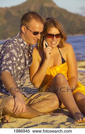 Hawaii, Oahu, Waikiki Beach, Couple Sitting On The Beach With Diamond Head In The Background, Woman Talking On Cellphone. View Large Photo Image Stock Photography - Hawaii, Oahu, Waikiki Beach, Couple Sitting On The Beach With Diamond Head In The Background, Woman Talking On Cellphone.. Fotosearch