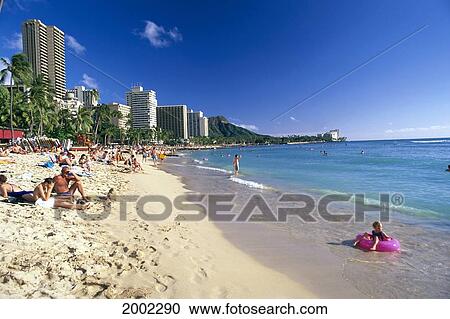 Stock Image - Hawaii, Oahu, Waikiki Beach, View Of Tourists Relaxing, Little Girl With Inner Tube. For Editorial Use Only.. Fotosearch