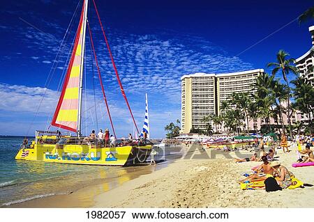 Stock Photo - Hawaii, Oahu, Waikiki Beach with catamaran along shoreline, tourists on sand. Fotosearch