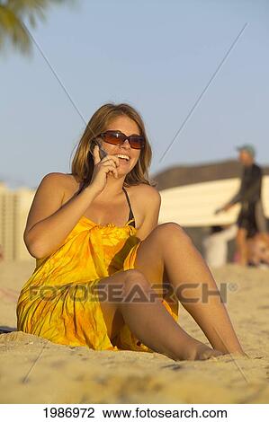 Hawaii, Oahu, Waikiki Beach, Woman Sitting On The Beach Talking On A Cellphone, Surfer In The Background. View Large Photo Image Stock Image - Hawaii, Oahu, Waikiki Beach, Woman Sitting On The Beach Talking On A Cellphone, Surfer In The Background.. Fotosearch
