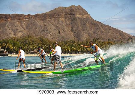Stock Image - Hawaii, Oahu, Waikiki, Competitors Of 'battle Of The Paddle' Catch Waves In Front Of Diamond Head. (Editorial Use Only). Fotosearch