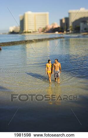 Hawaii, Oahu, Waikiki, Couple walking in shallow water at beach. View Large Photo Image Stock Photo - Hawaii, Oahu, Waikiki, Couple walking in shallow water at beach.. Fotosearch