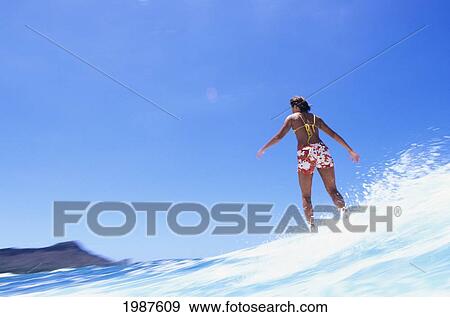 Stock Photo - Hawaii, Oahu, Waikiki, Girl Riding Wave, Diamond Head In Background. No Model Release. Fotosearch