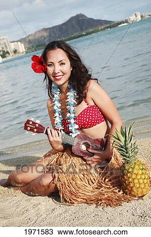 Stock Image - Hawaii, Oahu, Waikiki, Hula Dancer Holding Ukulele Along Beach, Diamond Head In The Distance.. Fotosearch