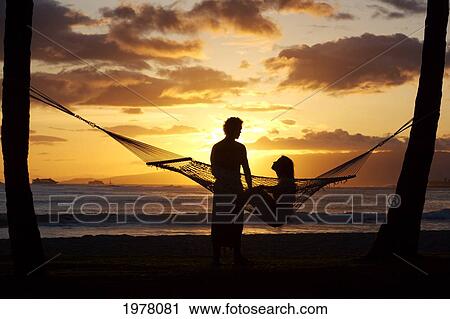 Hawaii, Oahu, Waikiki, Kapiolani Park, Silhouette Of Woman In Hammock And Man Standing Next To Her. View Large Photo Image Stock Image - Hawaii, Oahu, Waikiki, Kapiolani Park, Silhouette Of Woman In Hammock And Man Standing Next To Her.. Fotosearch